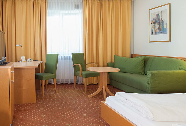 Hotelzimmer mit Doppelbett und Sofaecke