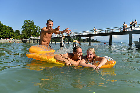 Besucher im Wasser mit Luftmatratze im Strandbad Friedrichshafen